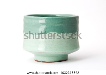 Green handmade pottery cup on white background