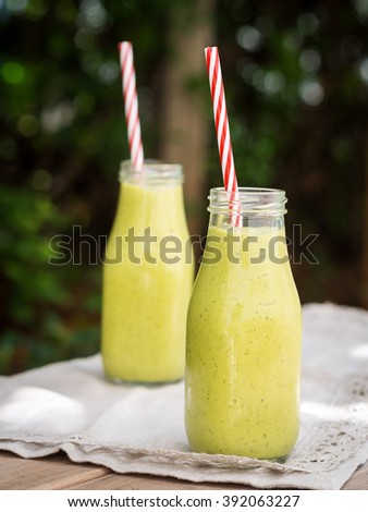 Green healthy smoothie  on a garden table. Vertical orientation.
