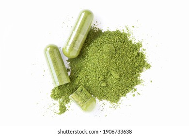 Green herbal capsule and dry plant powder isolated on white background. Top view. Flat lay.