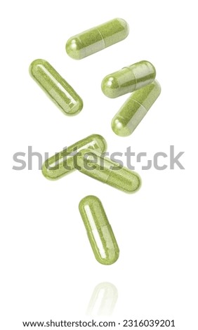 Green herbal capsule levitate isolated on white background.
