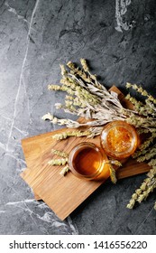 Green Herbal Greek Mountain Tea In Glass Cup On Wooden Board Over Dark Texture Background. Top View, Flat Lay