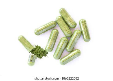 Green herbal powder capsule isolated on white background. Top view. Flat lay.