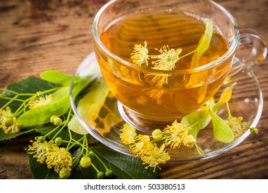 Green herbal tea with linden flowers on old wooden table, closeup