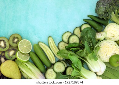 Green high fibre food for digestive health concept with fruit and vegetables on mottled blue background border. Foods also high in antioxidants, minerals and vitamins. Flat lay, top view, copy space.
