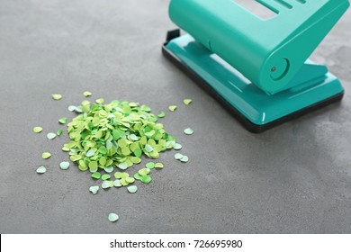 Green Hole Punch And Paper Confetti On Gray Table