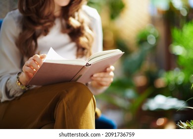 Green Home. Closeup on female with long wavy hair with book in the house in sunny day.