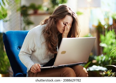 Green Home. Unhappy Modern Woman With Long Wavy Hair At Modern Home In Sunny Day Using Laptop.