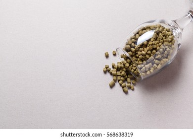 Green Hop Pellets Spilling Out From A Beer Glass Over A Gray Background