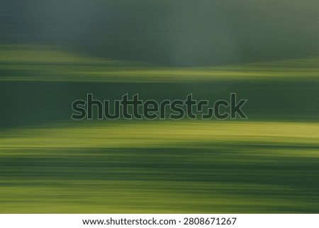 Green horizontal blurs and texture using intentional camera movement to create feeling of calm yet motion for background and similar use.