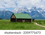 A green house in the Mormon Row district in Grand Teton National Park. Tetons mountain range in the background.