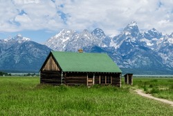 A Green House In The Mormon Row District In Grand Teton National Park. Tetons Mountain Range In The Background.