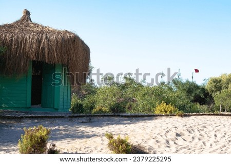 Green hut on the beach. Shack on the sand. Abandoned retreat corner. Blue sky. Thatched roof. Made with natural ingredients. Horizontal photo. No people, nobody. Nature. Seaside. Landscape.