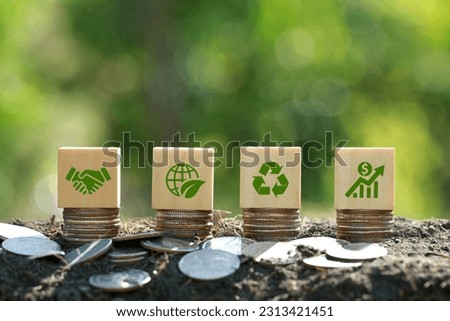 Green icons on wooden cubes on money coin stack. Green business growth. Finance sustainable development.growing money, finance and investment. Alternative sources of energy. Eco business investment
