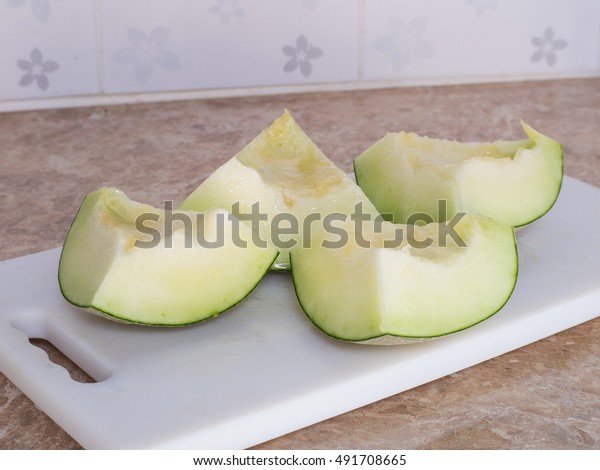 Green japanese melon was cut or divided\
on a white block in kitchen, Homemade\
style.