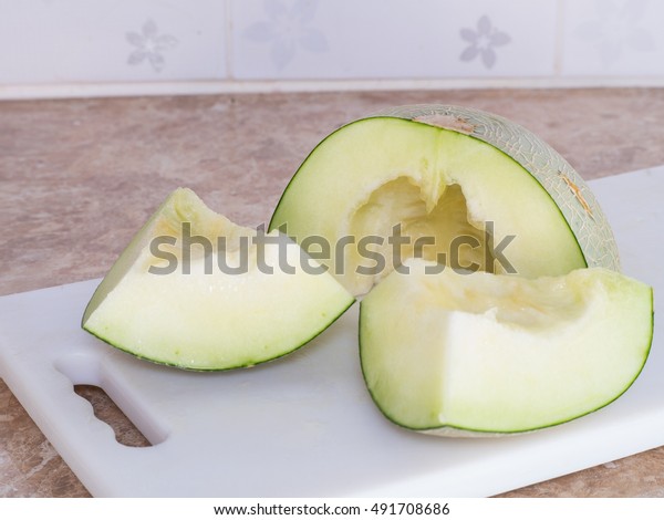 Green japanese melon was cut or divided
on a white block in kitchen, Homemade
style.