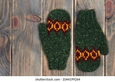 Green Knitted Mittens Handmade On A Wooden Background. View From Above.