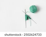 Green knitted wool on gray background with knitting needles for knitting warm clothes and hobbies needlework