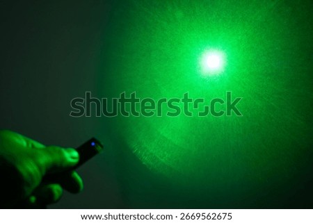 A green laser beam's diffraction pattern, creating a starburst effect with a bright central spot on a dark background.