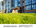 Green lawn against backdrop of residential building. Modern complex of multi-apartment residential buildings. New Residential Urban Regeneration Project. Landscape design for backyard garden. 