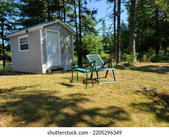 A Green Lawn Chair And Table Setup Outside Of A Shed In A Yard.