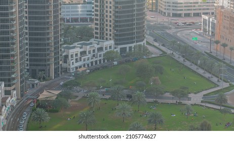 The Green Lawn And Palm Tree Shadow In Front Of Modern Skyscrapers Timealpse, Dubai, UAE. Aerial View To Busines Bay District Near Downtown