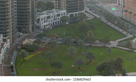 The Green Lawn And Palm Tree Shadow In Front Of Modern Skyscrapers Timealpse, Dubai, UAE. Aerial View To Busines Bay District Near Downtown