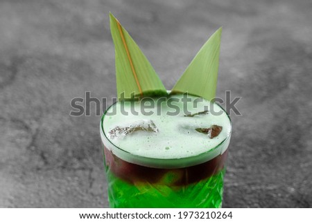 Green layered cocktail decorated with bamboo leaves on a gray background