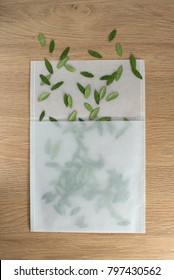 Green Leaf Confetti In Transparent Envelope On Wooden Table. Natural Design Concept. Creative Layout For Copy Space Or Mock-up. Celebration, Weddings, Valentines Day, Birthdays Etc. 