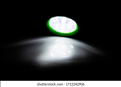 Green LED Torch Shining A Light On A White Surface In A Darkened Room