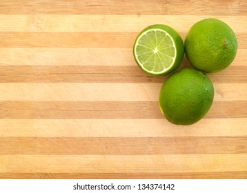 Green  Lemons Sit On A Worn Butcher Block Cutting Board