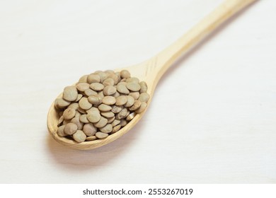 Green lentils in a wooden spoon, close-up. Cereals are useful for trace elements and vitamins. Variety in nutrition due to cereals. - Powered by Shutterstock