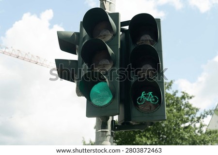 Green light active for both bicycle and car traffic lanes, captured in bright daytime.