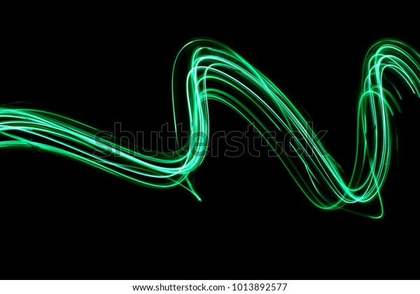 Green light painting\
photography - curves and waves of neon green light against a black\
background