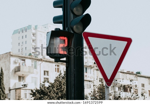 Green lighted Traffic light\
with the main road sign. Traffic light with stopwatch. 2 seconds to\
move.