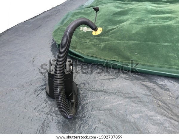 Green lilo air bed being blown by batteries operated\
air pump