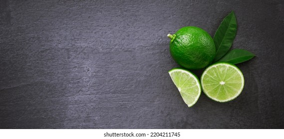 Green Lime With Slice And Green Leaf On Black Dark Background , Top View , Flat Lay.