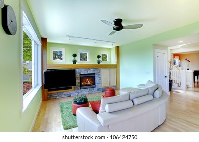 Green Living Room With Black TV And Beige Sofa With Fireplace.