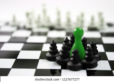 Green Ludo King And Chess Black Pawns Group Around Him And Stares Out Into The White Blurry Army