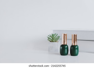 Green luxury nail polish, books and decorative plant isolated on white background. Clean and minimalist style for beauty concept with  mock up and copy space for branding 