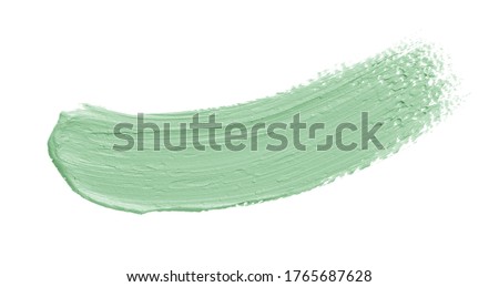 Green makeup cream swatch isolated on white background. Color correcting concealer smear smudge brushstroke. Makeup creamy texture
