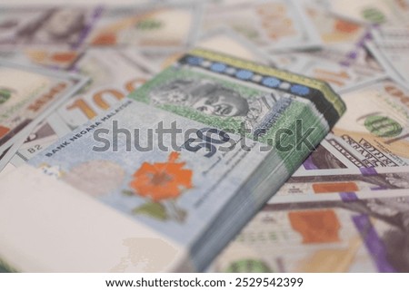 Green Malaysian Ringgit stacked on top of US dollar bills, highlighting global finance, currency exchange, and financial markets.