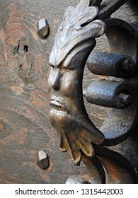 Green Man Cast Iron Decorative Door Handle Of Face Surrounded By Leaves. Detailed Closeup Of Naturalistic Pagan Symbol On Traditional Antique Wooden Door Background In South France