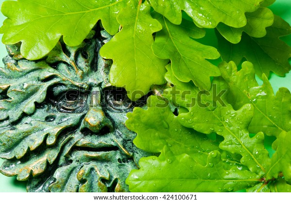 Green man pagan icon and oak leaves, close up image.
