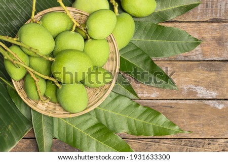 Green Mango and green leaf on Basket and old Wooden floor background,Group of Raw Mangoes organic with Sour and high vitamin C fruit for healthy.