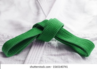 Green Martial Art Belt Tied In A Knot On White Gi In Background