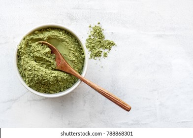 Green matcha tea powder with spoon on white concrete background. Top view. 