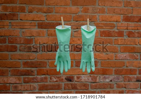 green medical gloves hang to dry against a brick wall in the spring during the coronavirus epidemic