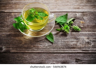 green melissa herbal tea in glass cup on wooden background