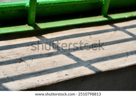 Green metal net window fence shadow on horizontal concrete wall surface background.
