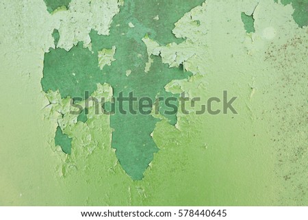 Green metal plate with cracked paint and big paint spots because of time as background, metal wall with rusty spots and cracked paint as texture, toned to color